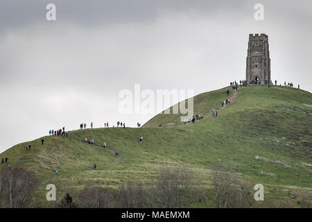 Les gens à pied jusqu'à St Michael's Tower sur le haut de Tor de Glastonbury, Somerset, que les prévisionnistes ont averti des conditions de conduite dangereuses pour les vacanciers de Pâques avec la neige et la pluie torrentielle sur le chemin. Banque D'Images