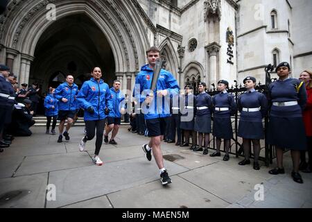 L'un des plus jeunes membres de la RAF, l'Aviateur-chef Adam Wood, 16 ans, (au centre) s'exécute avec la RAF100 Baton en dehors de la Cour royale de Justice de Londres, avant de la lancer et de relais Baton première jambe. Banque D'Images