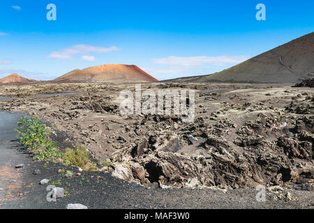 Paysage de lave de Timanfaya à Lanzarote, Espagne avec ciel bleu et la Caldeira Colorada l'arrière-plan. Banque D'Images