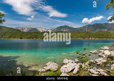 Vue sur le lac coloré à Garmisch-Partenkirchen, Allemagne Eibsee en été à un lointain montagnes avec quelques roches au premier plan. Banque D'Images