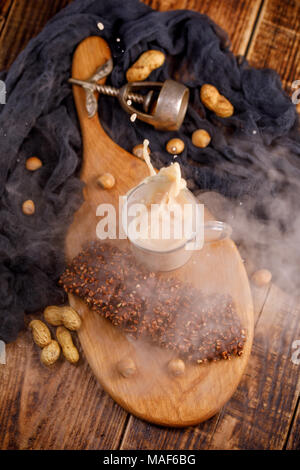 Délicieux petit déjeuner léger sur une table en bois, vue du dessus. Tabac, thé au lait et biscuits au chocolat avec des noix pour le petit-déjeuner est renversé à partir de la tasse. Banque D'Images