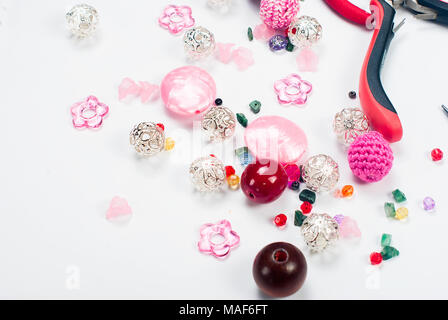 Perles colorées, pinces et autres accessoires pour les travaux d'aiguille sur fond blanc Banque D'Images