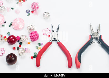 Perles colorées, pinces et autres accessoires pour les travaux d'aiguille sur fond blanc Banque D'Images