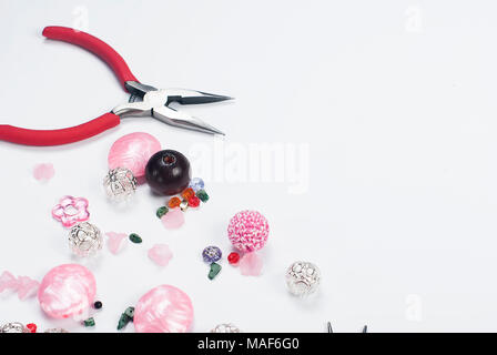 Perles colorées, pinces et autres accessoires pour les travaux d'aiguille sur fond blanc Banque D'Images