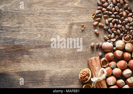 Les écrous différents sur une table en bois. Le cèdre, noix de cajou, noisettes, et une cuillère sur la table. Beaucoup de noix en coque sont et chistchenyh on a wooden background Banque D'Images