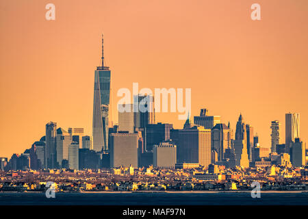 Les tours de New York skyline avec Brooklyn borough de faible hauteur à l'avant-plan, comme vu au lever du soleil, de Sandy Hook (New Jersey). Banque D'Images