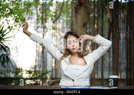 Young businesswoman stretching elle-même et de bâiller au travail, à l'état prêt pour travailler. Banque D'Images