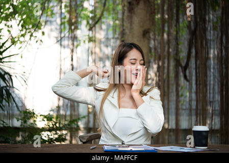 Young businesswoman stretching elle-même et de bâiller au travail, à l'état prêt pour travailler. Banque D'Images