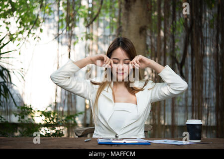 Young businesswoman stretching elle-même et de bâiller au travail, à l'état prêt pour travailler. Banque D'Images