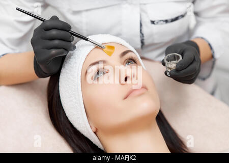 Cosmetologist professionnel faisant l'application et du visage masque peeling anti-acné. Gorgeous woman lying, relaxant et obtenir les procédures cosmétologie, rejuve Banque D'Images