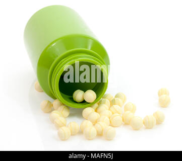 Les comprimés de probiotiques ronde jaune déversant du vert bouteille de médicament contre l'arrière-plan blanc. Banque D'Images