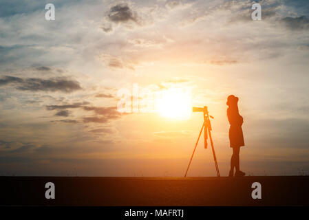 Silhouette d'un photographe tire un coucher du soleil. Banque D'Images