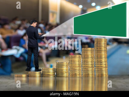 Asian businessman standing sur la pile de pièces d'or et à l'aide de la tablette présente le livre vert sur l'écran résumé photo floue de salle de conférence ou Banque D'Images