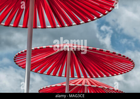 Trois parasols rouges contre un blue cloudy sky Banque D'Images