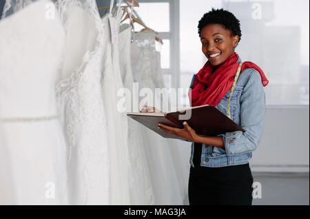 Femme robes de designer avec diary travaillant dans une boutique. Mariage femme couturière avec journal en magasin. Banque D'Images