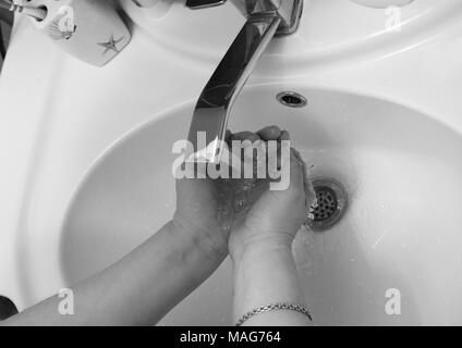 Photo en noir et blanc de se laver les mains dans la salle de bains. Banque D'Images