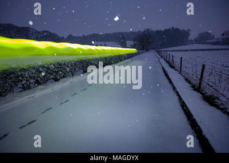 Flintshire, Pays de Galles, Royaume-Uni 2e avril 2018, UK Weather : un affouillement Easter Bank Holiday se termine par un agent d'alerte météorologiques rencontrés pour la pluie et la neige pour les vacances de banque lundi. Une personne qui marche le long d'un chemin rural à Pantasaph avec un parapluie jaune comme il tire sur l'image en raison de la longue exposition, Flintshire, Â©/DGDImages Alamy Live News Banque D'Images