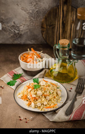 Pilaf de boulgour au poulet dans une assiette et un bol de salade de chou sur un béton fond brun Banque D'Images