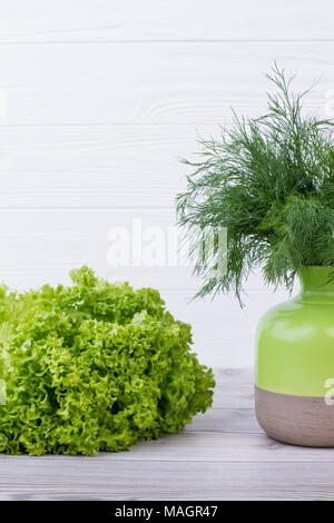 Belle composition avec des herbes vertes. Laitue fraîche sur fond de bois. Bouquet d'aneth en deux-ton vase en céramique. La nourriture végane concept. Banque D'Images