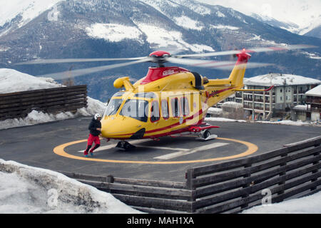 PILA, ITALIE-MARS 29, 2018 : hélicoptère de sauvetage gérer une urgence sur la pente de ski sur neige Banque D'Images