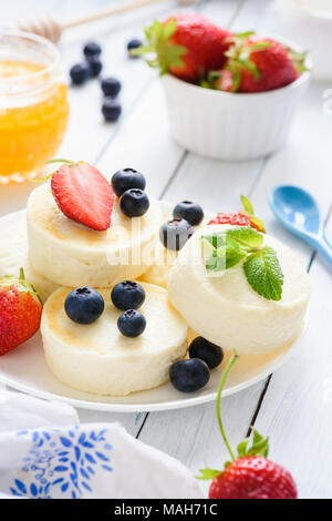 Mini cheesecakes avec les baies fraîches et de menthe sur fond blanc. Selective focus Banque D'Images