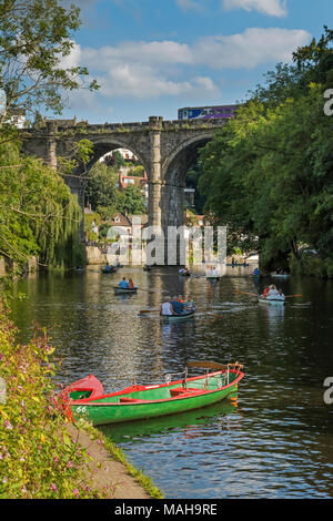 Les gens se détendre et navigation dans les barques sur la rivière Nidd sous ciel d'été bleu, comme le train passe au-dessus de la pittoresque ville de pont sunny Knaresborough, England, UK Banque D'Images