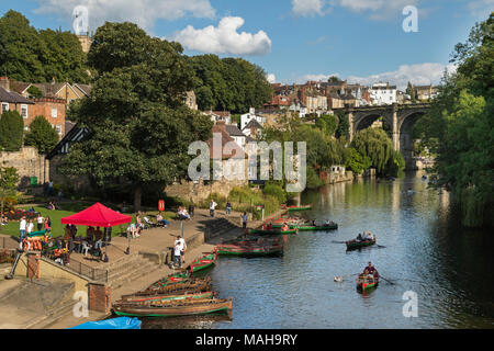 Les gens se détendre par Riverside et navigation dans les barques sur la rivière Nidd sous ciel bleu ensoleillé panoramique - vue d'été par pont, Knaresborough, England, UK. Banque D'Images