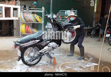 Un homme lave une moto, le moyen de transport le plus populaire, Kampong Thom, au Cambodge, en Asie Banque D'Images