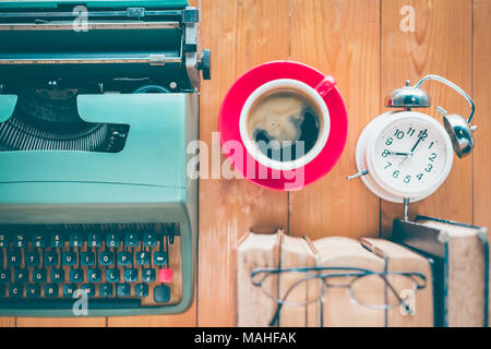 Vieille machine à écrire avec une tasse de café et des livres sur la table en bois Banque D'Images