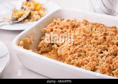 Crumble aux pommes fraîchement cuits dans un plat allant au four, et une partie sur une assiette. Selective focus Banque D'Images