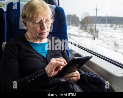 Middle-aged woman using tablet caucasiam dans le train Banque D'Images