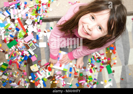 Young smiling girl looking at camera jouant avec lego Banque D'Images