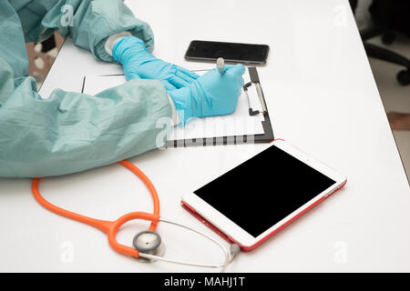 Femme médecin écrit quelque chose assise à son bureau. Concept de la santé. Banque D'Images