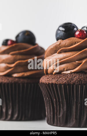 Petits gâteaux au chocolat avec de la crème, et les baies de raisin isolated on white Banque D'Images