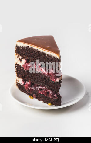 Vue rapprochée de cerise-chocolat gâteau sur une assiette isolated on white Banque D'Images