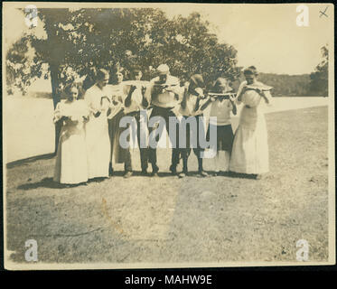 Titre : groupe de jeunes hommes et femmes associés à la famille Lyon eating watermelon près d'un lac. . Vers 1910. Banque D'Images