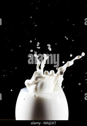 Lait/blanc splash liquide à partir du verre sur fond noir Banque D'Images