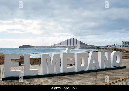 Le signe tridimensionnel qui dit "El Medano", placé sur la longue promenade qui longe la côte et de la plage, avec Montana Roja à l'arrière Banque D'Images