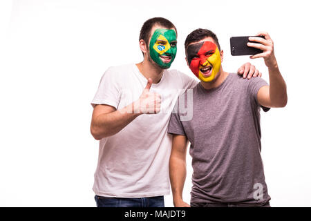 Les fans de football supporters avec visage peint d'équipes nationales du Brésil et de l'Allemagne prendre isolé sur blanc selfies Banque D'Images