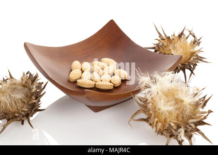 Le chardon de lait séché avec des plantes chardon-marie comprimés dans bol en bois. Isolé sur fond blanc. La médecine de fines herbes. Banque D'Images