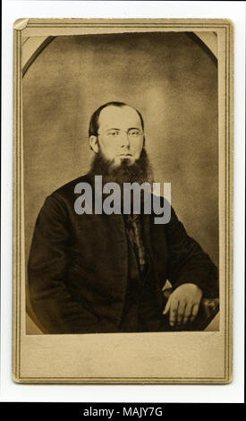 Portrait de mi-longueur d'un homme barbu portant un costume et lunettes avec son bras droit en appui sur une table. "Père Bannon forme après son retour de la guerre. Un de mes meilleurs amis" (écrit sur le verso). 'A.T. Pas de photographe URIE 1 Nord 4ème rue ST. LOUIS' ve (imprimé au verso). Jeune Père Bannon en 1861. Titre : Le Père John Bannon. . 1861. A.T. Urie, Saint Louis Banque D'Images