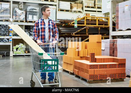 Homme choisit et achète des biens dans un supermarché de la construction Banque D'Images