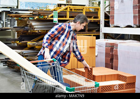 Homme choisit et achète des briques dans un supermarché de la construction Banque D'Images