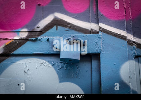 Close up d'un cadenas sur une porte, peint à la bombe des graffitis. Banque D'Images