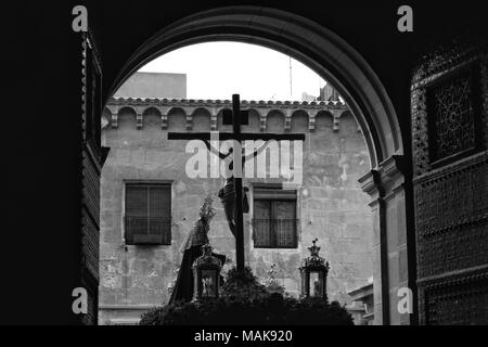 Elche, Espagne- 27 mars 2018 : le Christ en procession de la Semaine Sainte à Elche dans l'après-midi. Ancienne façade et les portes de l'église ouverte. Photo monochrome Banque D'Images