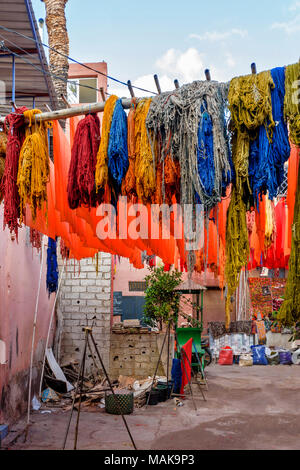 Place JEMAA EL FNA MARRAKECH MAROC Souk Médina écheveaux de laine et de tissus en laine teints multicolores suspendus à des poteaux et le séchage au soleil Banque D'Images