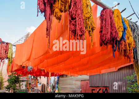 Place JEMAA EL FNA MARRAKECH MAROC Souk Médina UNE COUR AVEC laine teints multicolores ET FEUILLES ORANGE TENTURE des poteaux pour sécher au soleil Banque D'Images