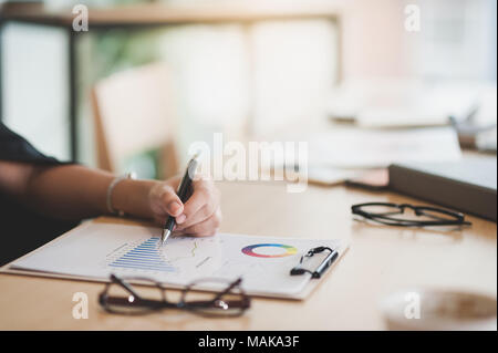 Main femme écrit une idée sur presse-papiers tout en restant assis dans la salle de réunion. Journée de l'entreprise sur le mode de vie Banque D'Images