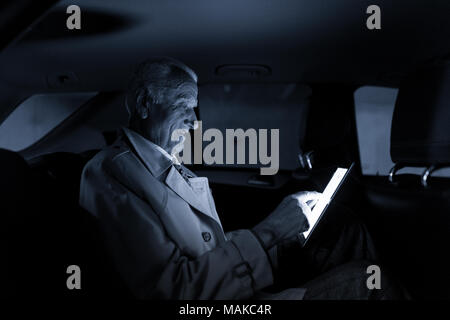 Businessman with a digital tablet assis dans le siège arrière d'une voiture Banque D'Images