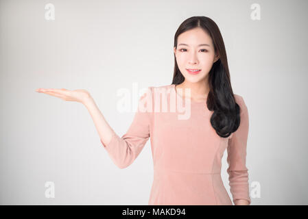 Belle femme asiatique avec sourire heureux de montrer ou de présentation de vente de produit promotion publicité concept avec main ouverte geste isolé sur bac blanc Banque D'Images